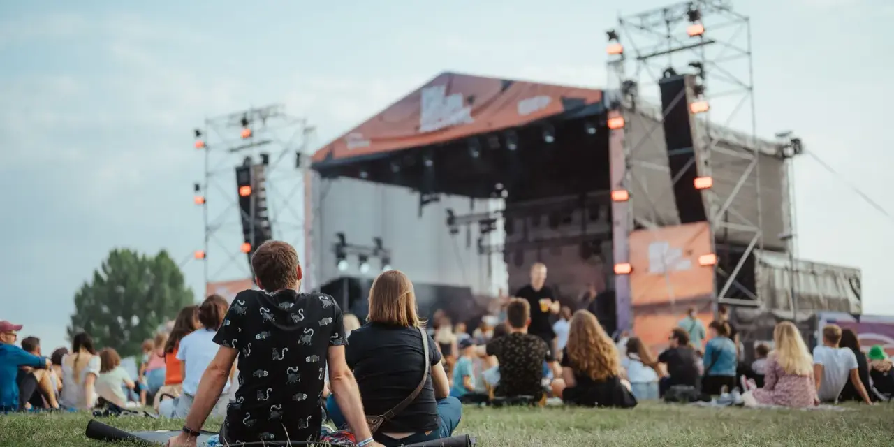 Widownia siedzi na trawie przed sceną podczas Enea Festival Baranowo.