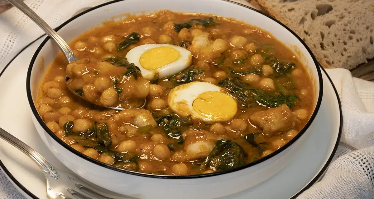 Potaje de garbanzos con bacalao y huevo duro en un cuenco blanco.