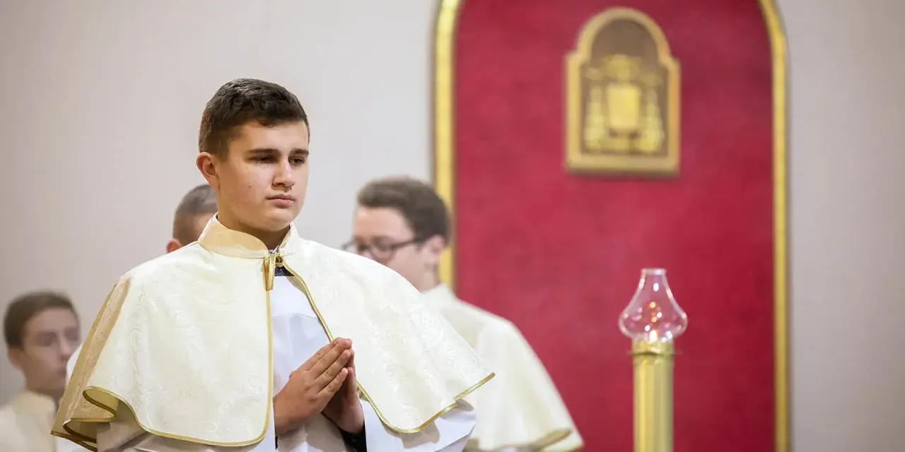 Junge Männer in festlicher Kleidung, die auf ihre Diakon Ausbildung vorbereitet werden. Sie stehen betend in einer Kirche.
