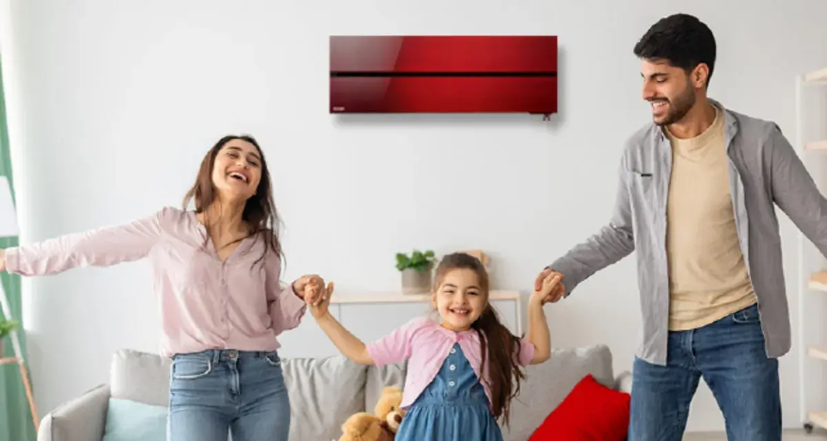 Familia feliz bailando en una sala con aire acondicionado inverter rojo. Disfrutan del confort y bajo consumo kwh.