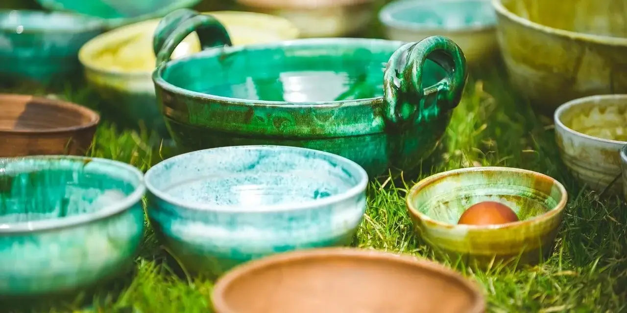 Varietà di ciotole in ceramica smaltata, che ricordano diversi tipi di argilla per modellare, disposte sull'erba.