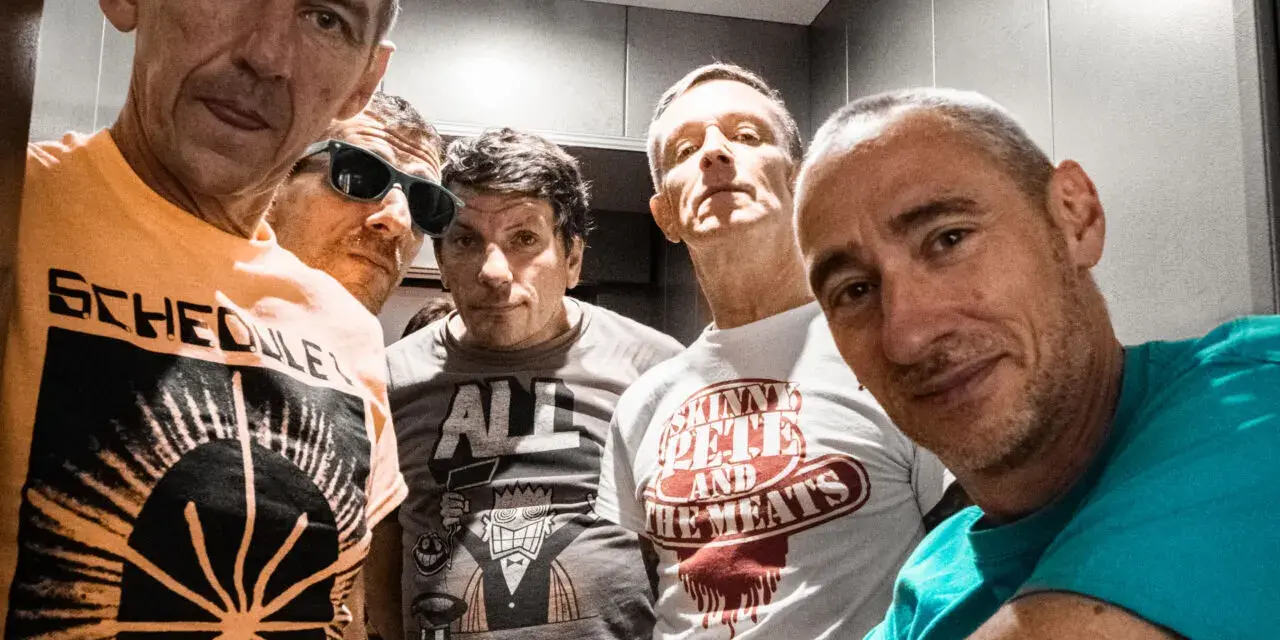 Cinq hommes aux têtes brûlantes, certains souriants, d'autres plus intenses, posent pour un selfie. Leurs t-shirts affichent des graphismes variés.