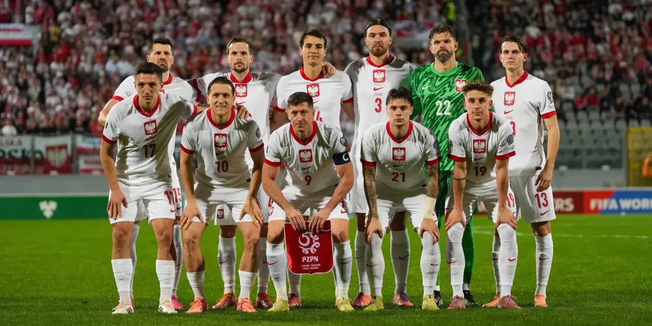Reprezentacja Polski zawodnicy w białych strojach, gotowi do gry. Na murawie widać dumę i determinację.