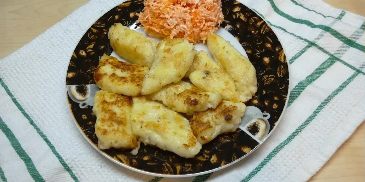 Placuszki z farszu na ruskie na talerzu z tartą marchewką.