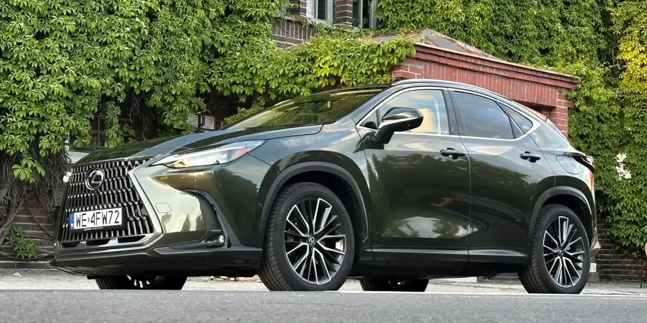 Ciemnozielony Lexus NX 450h+ plug-in zaparkowany przed budynkiem porośniętym bluszczem.