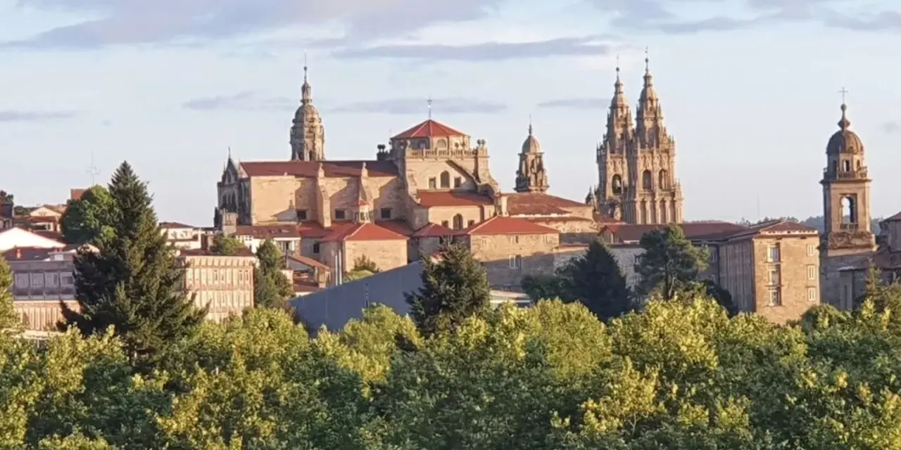 Majestatyczna katedra w Santiago de Compostela, cel pielgrzymek, wyłania się zza zieleni drzew.