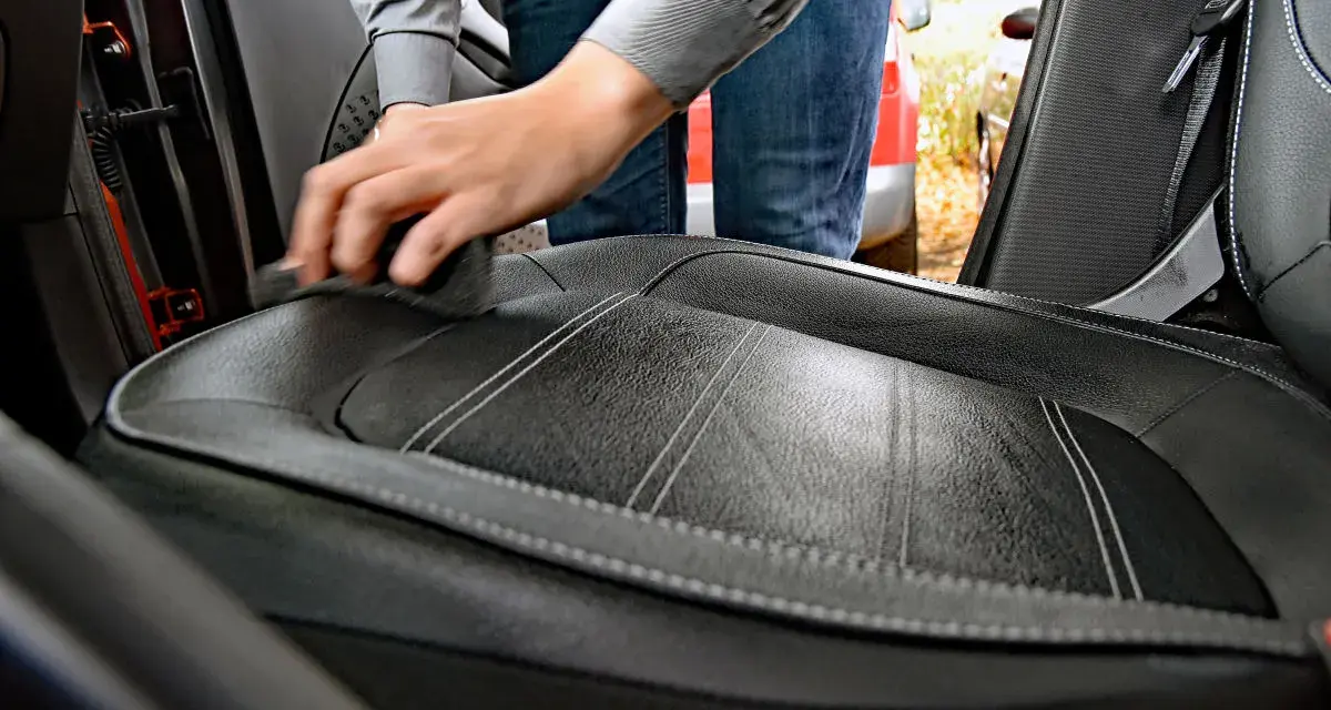 Hand reinigt Autositz aus Leder mit einem Tuch. Hausmittel für Leder reinigen sind eine gute Wahl.