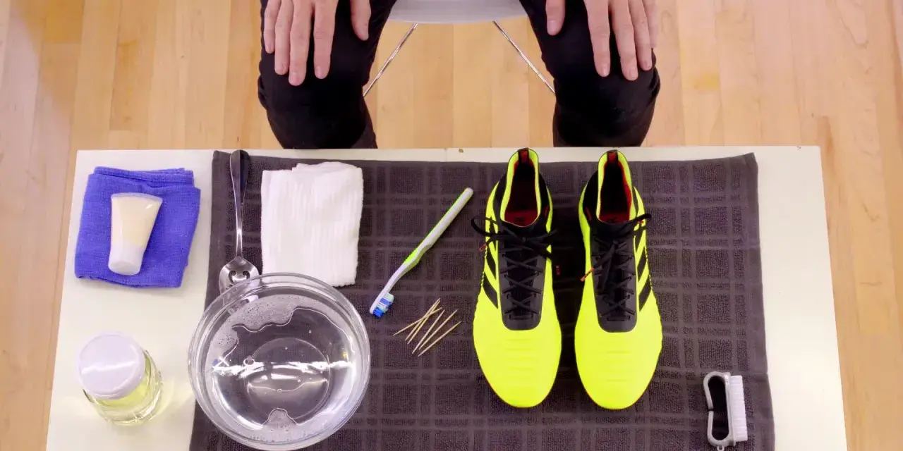 Kit per pulire le scarpe Adidas gialle: spazzolino, acqua saponata, panni e crema.