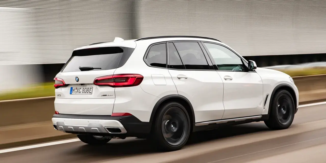 Białe BMW X5 M50d pędzi po autostradzie, zostawiając za sobą rozmyte tło.