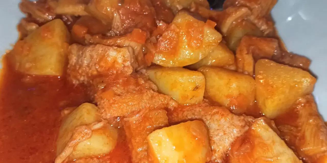Un piatto fumante di trippa con patate, un classico della cucina italiana, condito con un sugo rosso saporito.