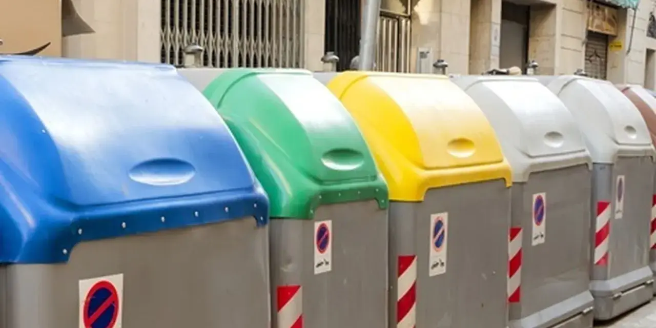 Fila de contenedores de reciclaje de Ecoembes en la calle: azul, verde, amarillo y grises.