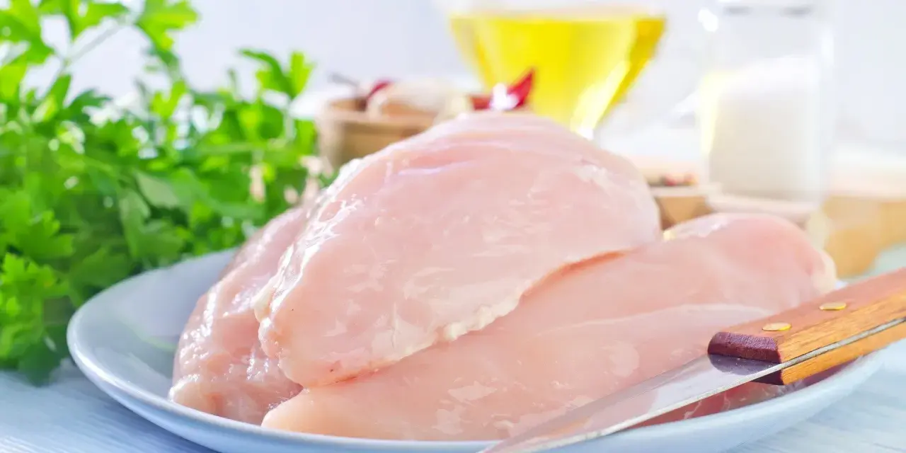 Surowe filety z kurczaka na talerzu, gotowe do przygotowania. Niska zawartość kcal sprawia, że to zdrowy wybór.