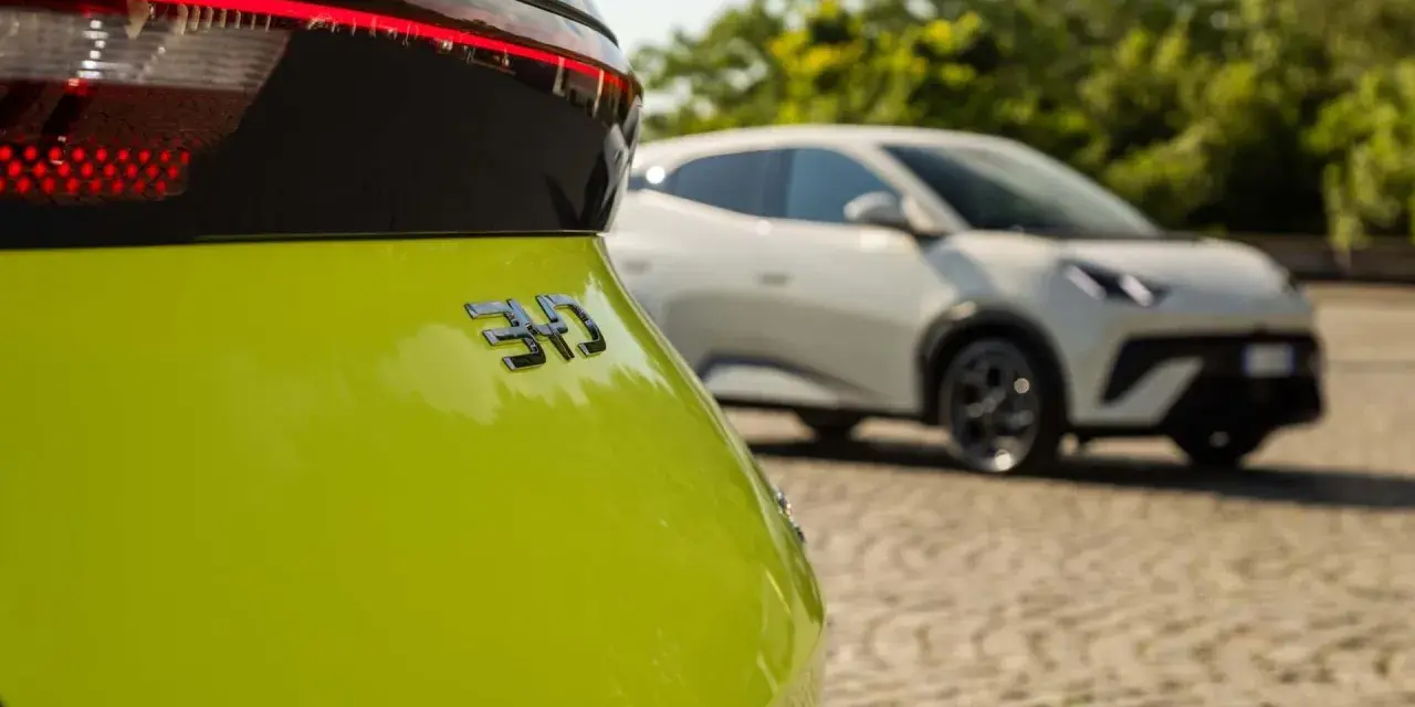 Jasnozielony samochód elektryczny BYD z napisem "310" na klapie bagażnika, w tle biały samochód.