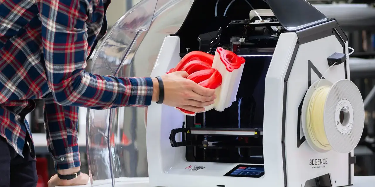 Inżynier wyjmuje z drukarki 3D skomplikowany element, pokazując potencjał druku 3D w przemyśle.