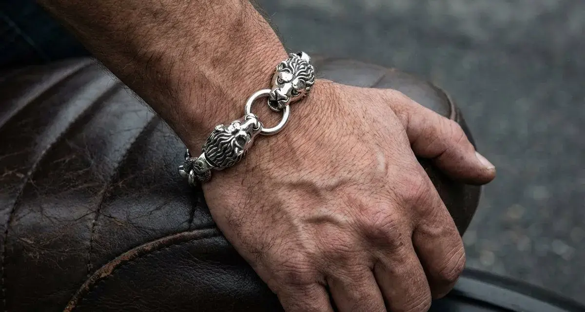 Męska dłoń z bransoletą z lwimi głowami, symbolizującą gest, kiedy mężczyzna daje kobiecie biżuterię.