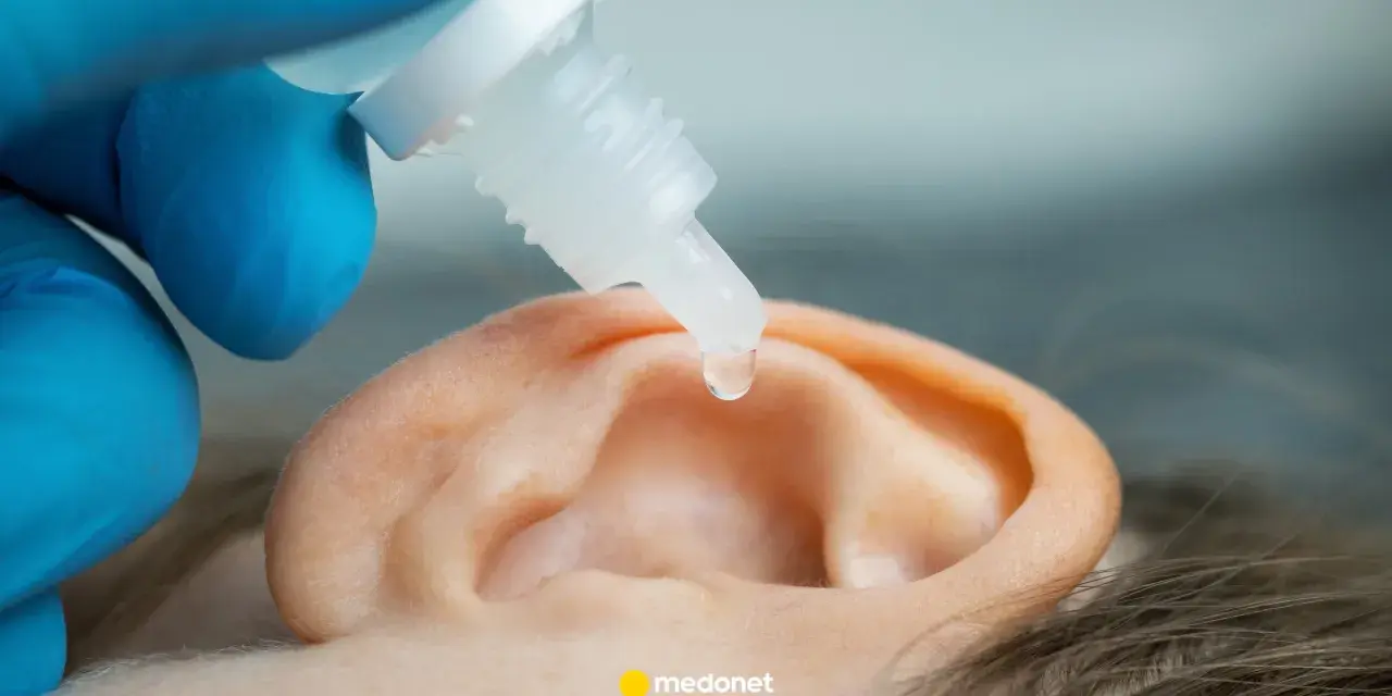 Kropla leku spada do ucha, które jest leczone.