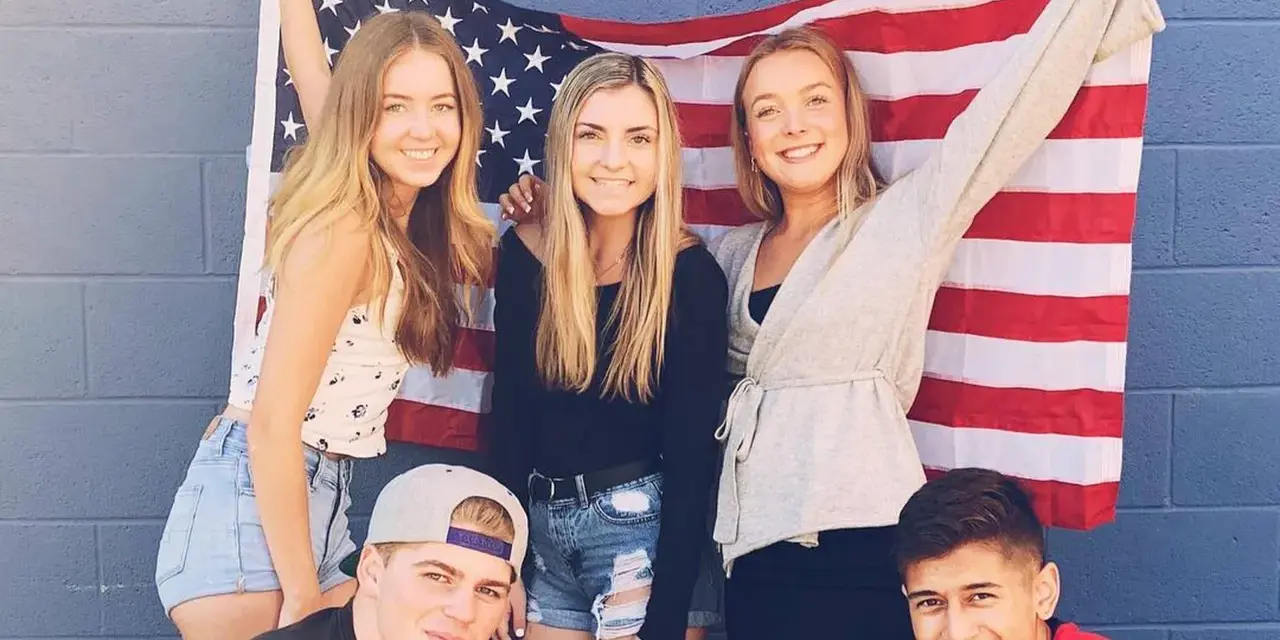 Freunde feiern ihr High School Jahr in den USA vor einer amerikanischen Flagge.