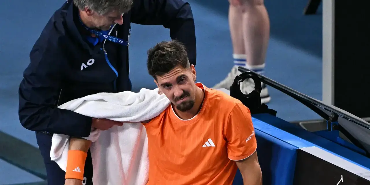 Tenisista z pomarańczową opaską na przedramieniu podczas Australian Open 2024 otrzymuje pomoc od fizjoterapeuty.