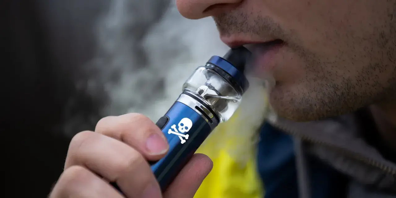 Persona vapeando un dispositivo con calavera, advirtiendo sobre los vapear efectos secundarios.
