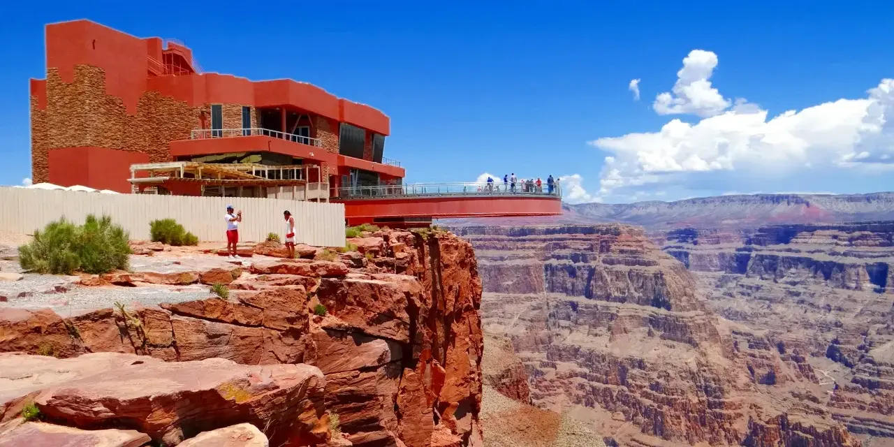 Widok na **great canyon** z czerwonego tarasu widokowego. Ludzie podziwiają majestatyczne formacje skalne pod błękitnym niebem.