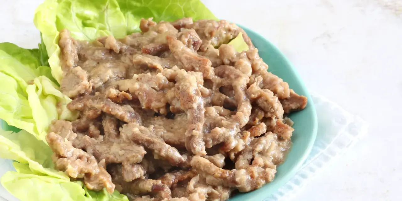 Straccetti di manzo succulenti serviti su foglie di lattuga fresca, un piatto invitante e saporito.