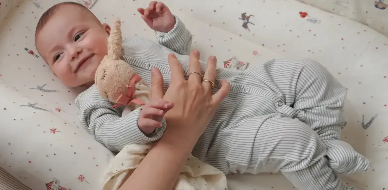 Uroczy niemowlak w pajacyku leży w łóżeczku. Dowiecie się, jak ubrac dziecko do spania, by było mu wygodnie.