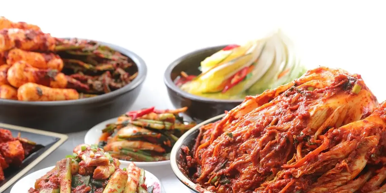 Różne rodzaje kimchi w miskach i na talerzach, w tym cała główka kapusty.