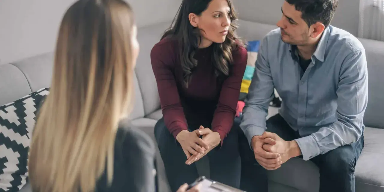 Un couple discute avec un psychiatre lors d'une séance de thérapie de couple.
