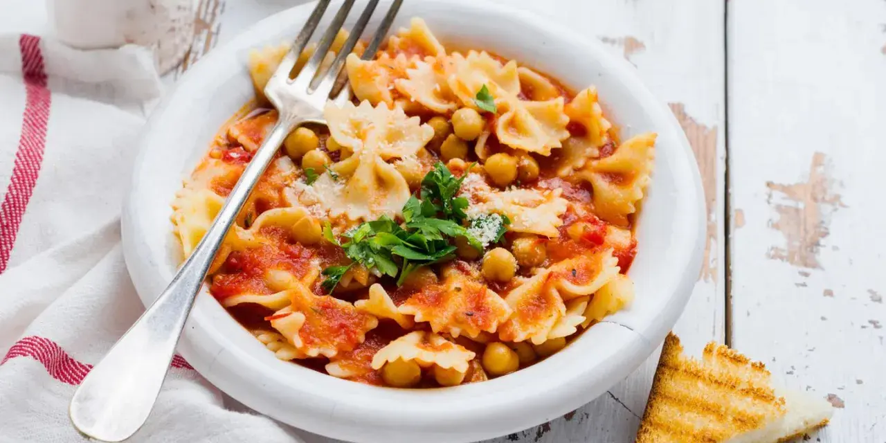Farfalle-Pasta mit Kichererbsen in Tomatensauce, garniert mit Petersilie und Parmesan. Ein einfaches ceci rezept, perfekt für ein schnelles Mittagessen.