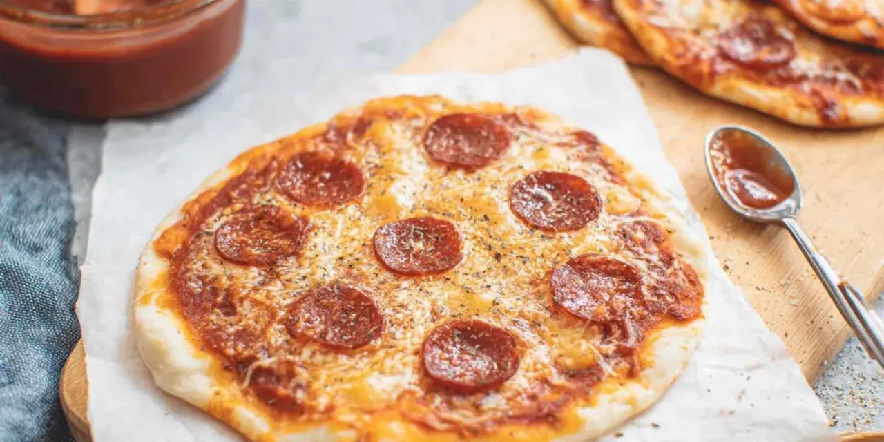 Pyszna pizza z tortilli na patelni, z serem i pepperoni, obok sos w miseczce.
