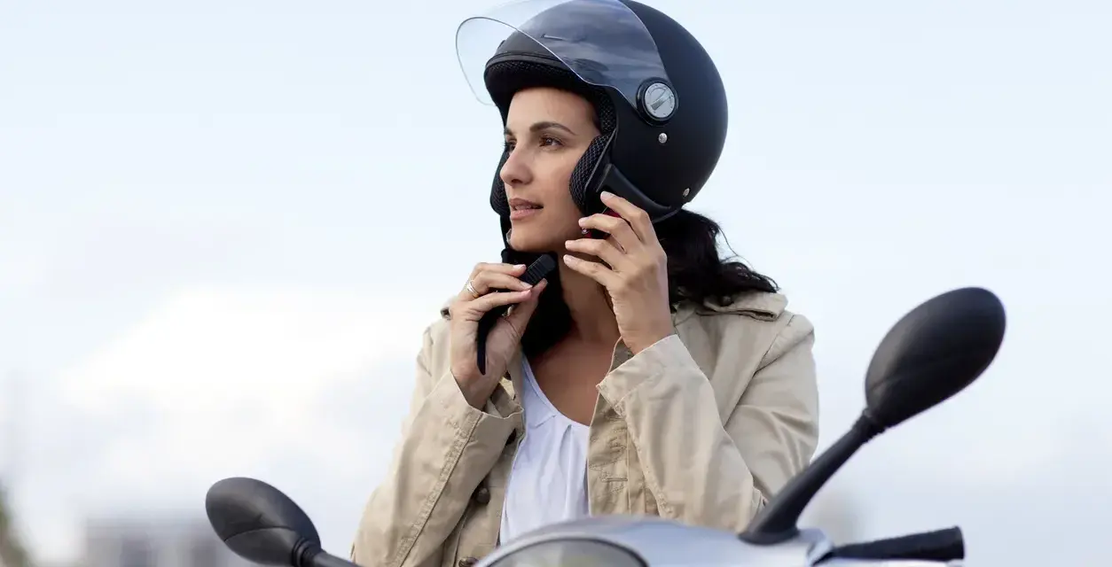 Donna con casco da moto nero, pronta a partire. Non è un luogo dove si buttano i caschi da moto, ma un simbolo di sicurezza.