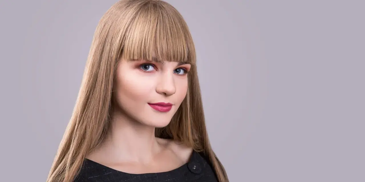 Blondynka z prostą grzywką, która podkreśla jej niebieskie oczy. Różne rodzaje grzywek mogą całkowicie odmienić wygląd.