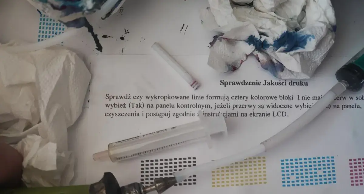 Narzędzia do automatycznego czyszczenia drukarki Brother: strzykawka, papierowe ręczniki z atramentem i instrukcja "Sprawdzenie Jakości druku".