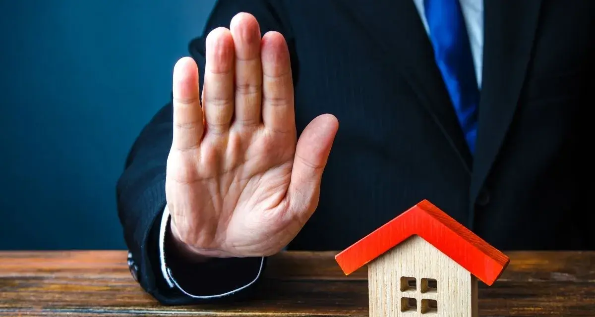 Main tendue, un homme en costume bloque une petite maison. Mon ex refuse la désolidarisation, le bien reste bloqué.
