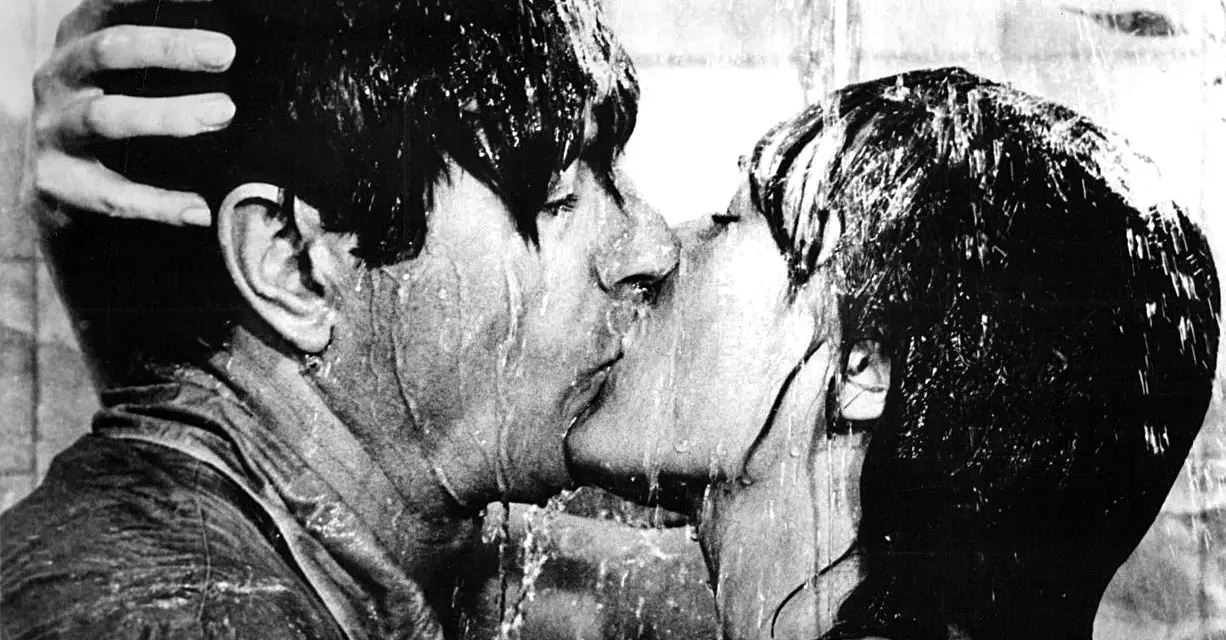 Una pareja se besa apasionadamente bajo la ducha, un momento íntimo que captura la esencia de qué es un beso francés.