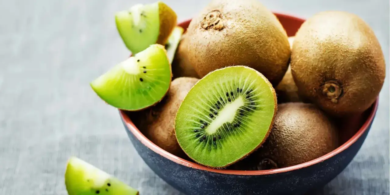 Miseczka pełna kiwi, jedno przekrojone na pół, pokazuje soczysty miąższ. Czy można jeść kiwi ze skórką? Tak, jest jadalna i pełna witamin!