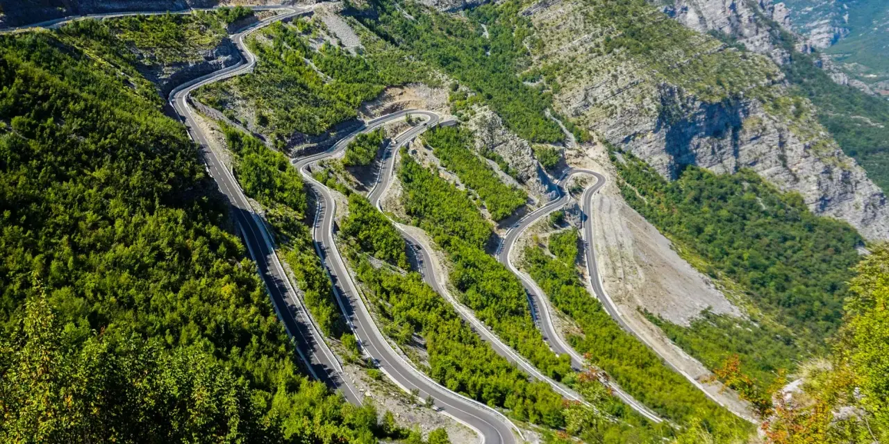 W serpentynach albania trasa pnie się po stromych zboczach gór, otoczona bujną zielenią.