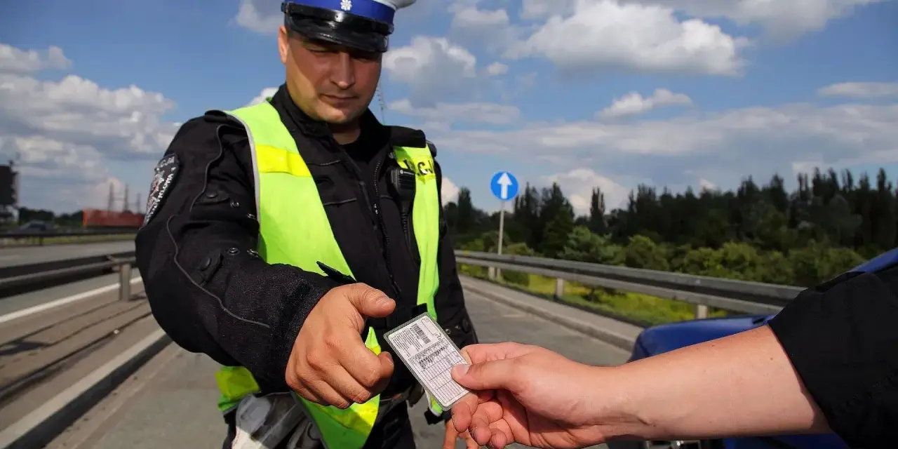 Policjant w kamizelce odblaskowej prosi o okazanie dokumentów. Czy trzeba mieć przy sobie prawo jazdy? Tak, podczas kontroli drogowej.