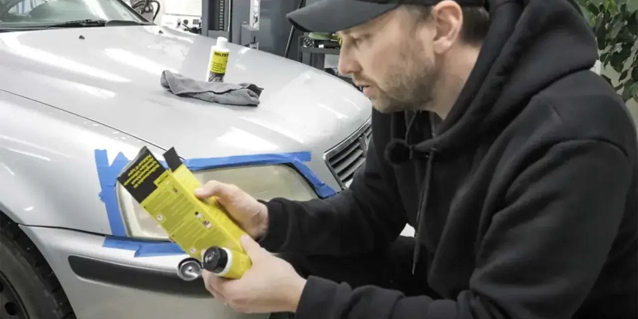Man förbereder polering strålkastare biltema. En flaska med produkt och trasa ligger på bilen.