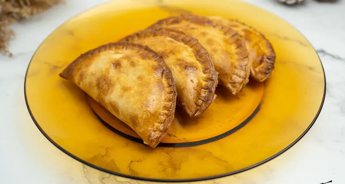Empanadillas doradas y crujientes, recién hechas en freidora de aire, servidas en plato ámbar.