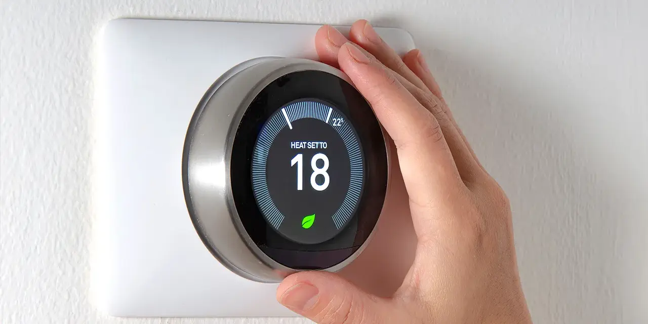 Una mano regola il termostato per impostare la temperatura desiderata, mostrando a cosa serve il termostato: controllare il riscaldamento per il comfort.