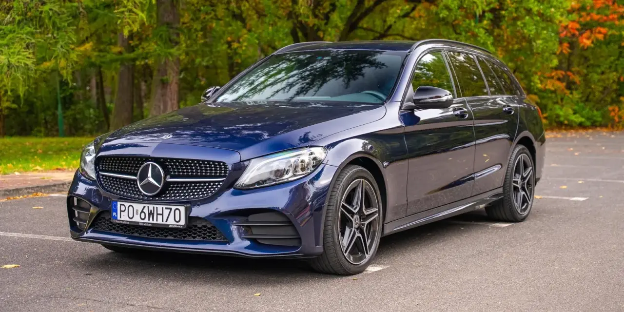 Granatowy Mercedes C klasa W205 kombi zaparkowany na tle jesiennego lasu.