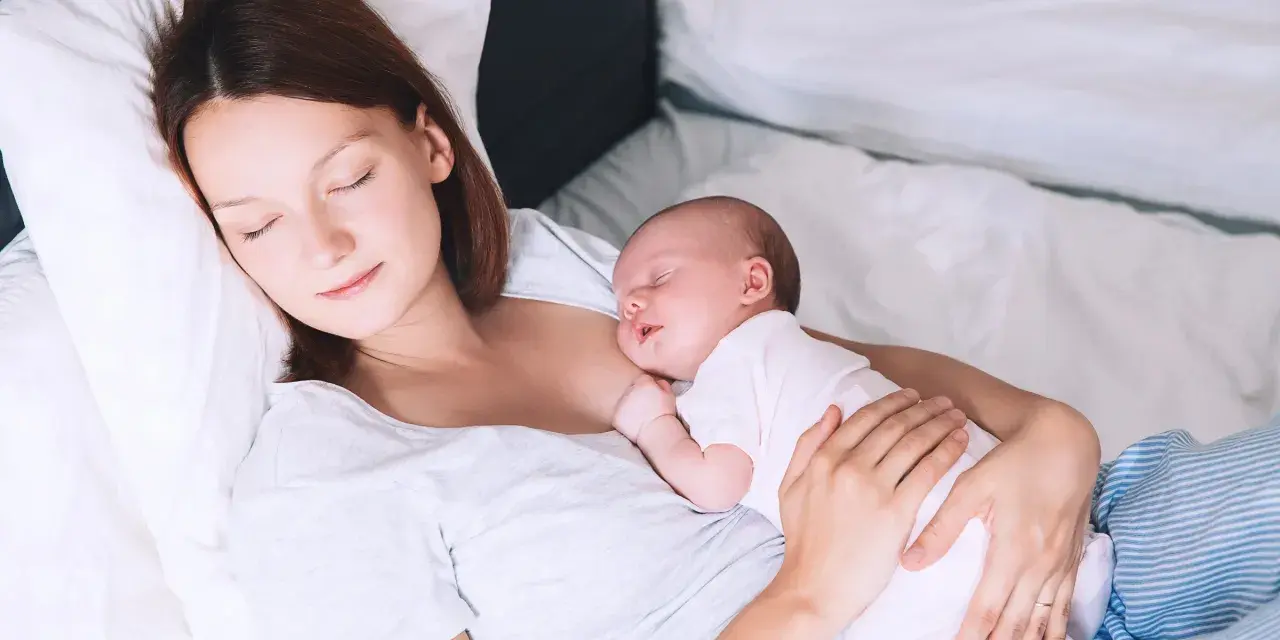 Matka śpi z dzieckiem przy piersi, doświadczając piękna laktacji.