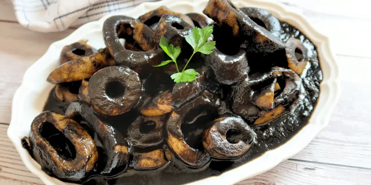 Calamares en su tinta, un plato tradicional español, servido en una fuente blanca con perejil fresco.