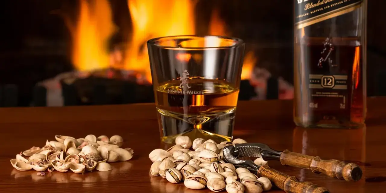 Przy kominku, kieliszek Johnnie Walker i pistacje. Idealny wieczór, czy whisky się chłodzi?