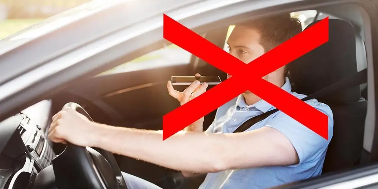 Uomo al volante che usa il cellulare, vietato dall'art. 173 CDS. La croce rossa indica il divieto.