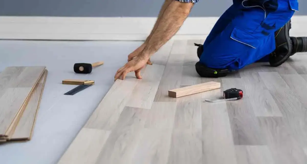Installazione di un nuovo pavimento in laminato, un passo fondamentale per come isolare il pavimento dal freddo. Attrezzi da lavoro a portata di mano.