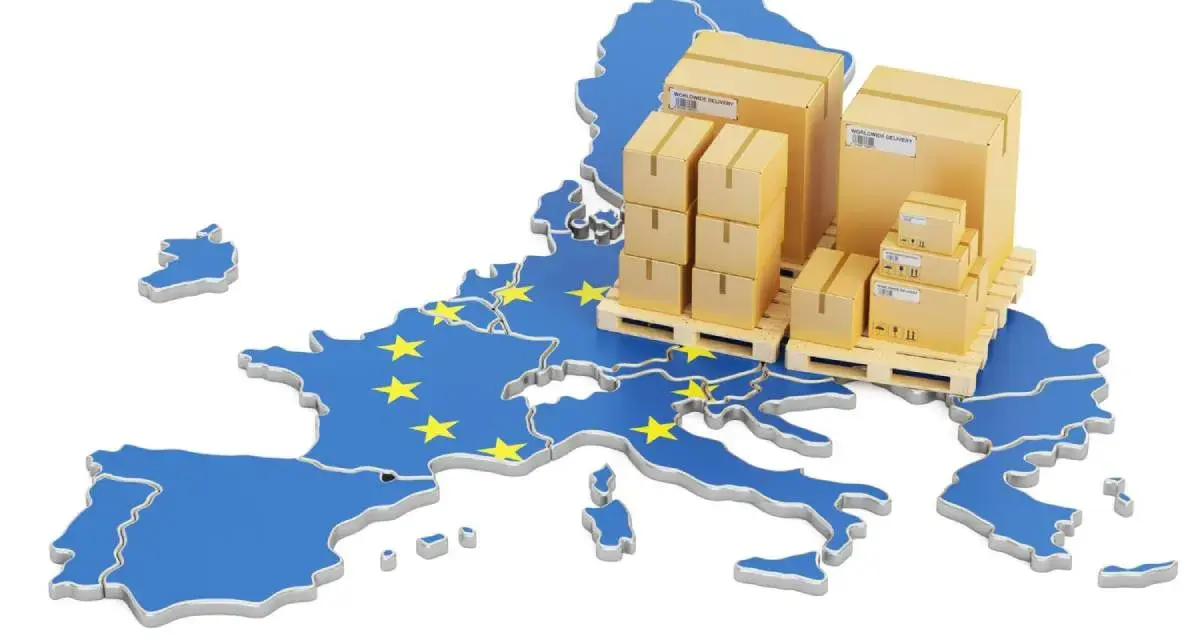 Cajas apiladas sobre palets, sobre un mapa de la Unión Europea con estrellas amarillas. Representa la logística y el comercio, y te preguntas: ¿qué es el VAT en este contexto?