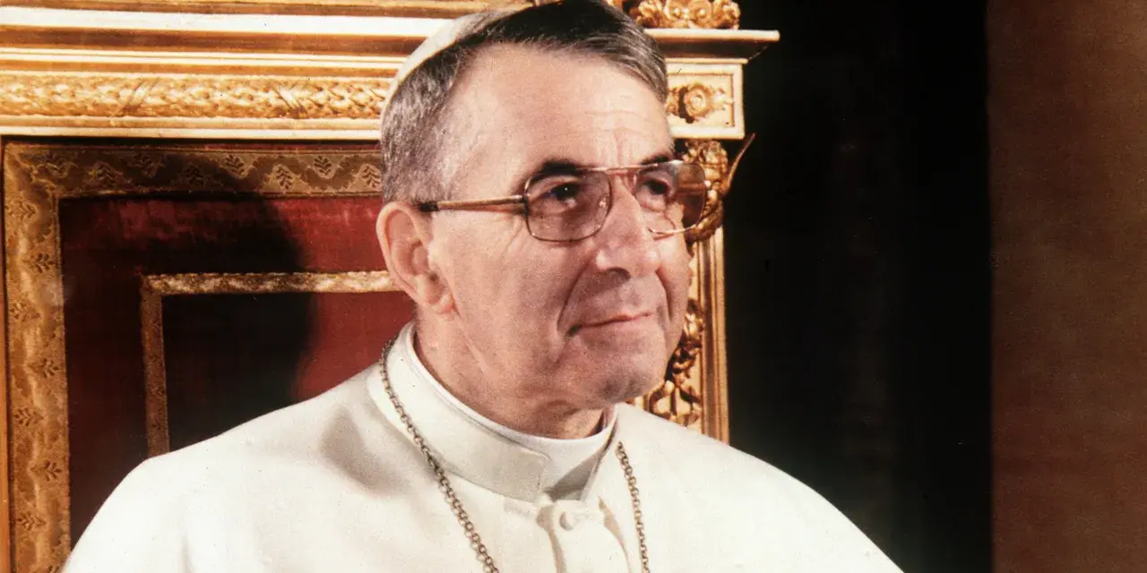 Papież Jan Paweł I, który był papieżem przed Janem Pawłem II, w białej sutannie i okularach.