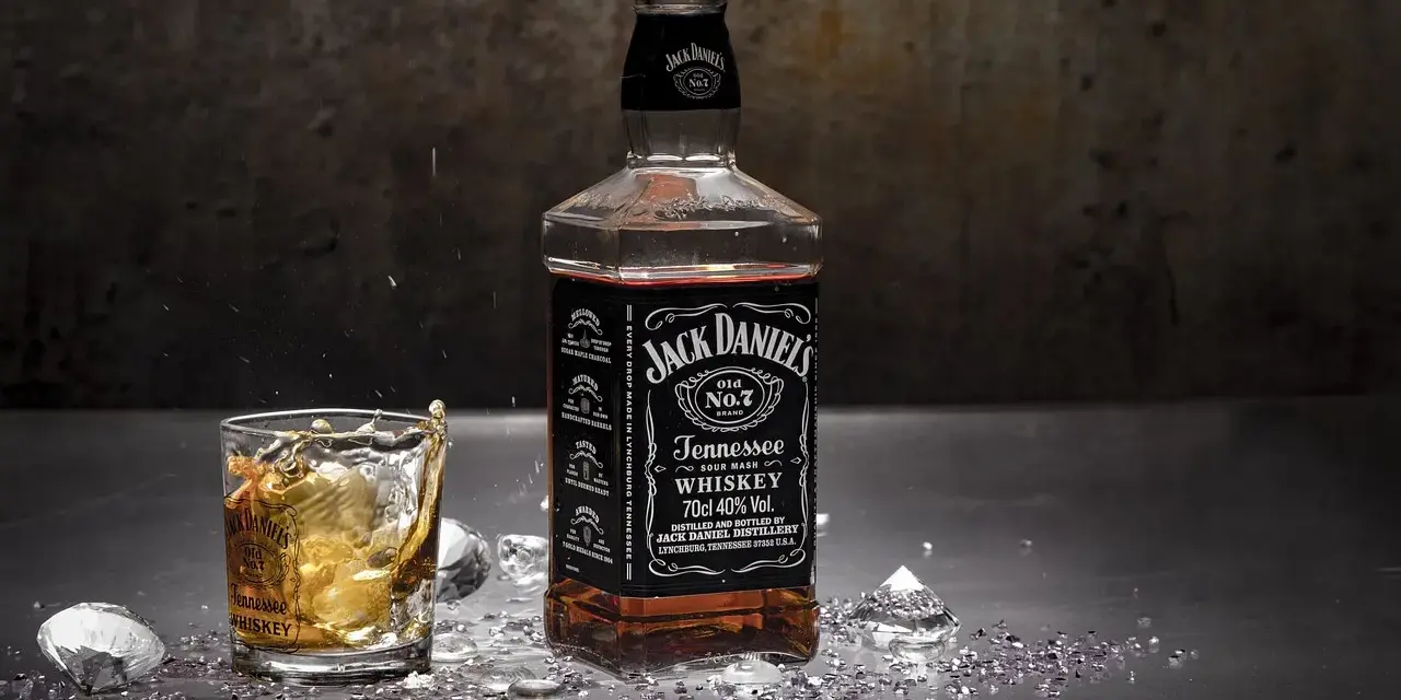 Butelka Jack Daniel's i szklanka z whisky, w której widać plusk. To klasyczny, old fashioned przepis na drinka.